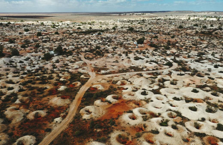 Aerial photograph showing hundreds, possibly thousands of holes dug into the baked landscape of outback Australia.